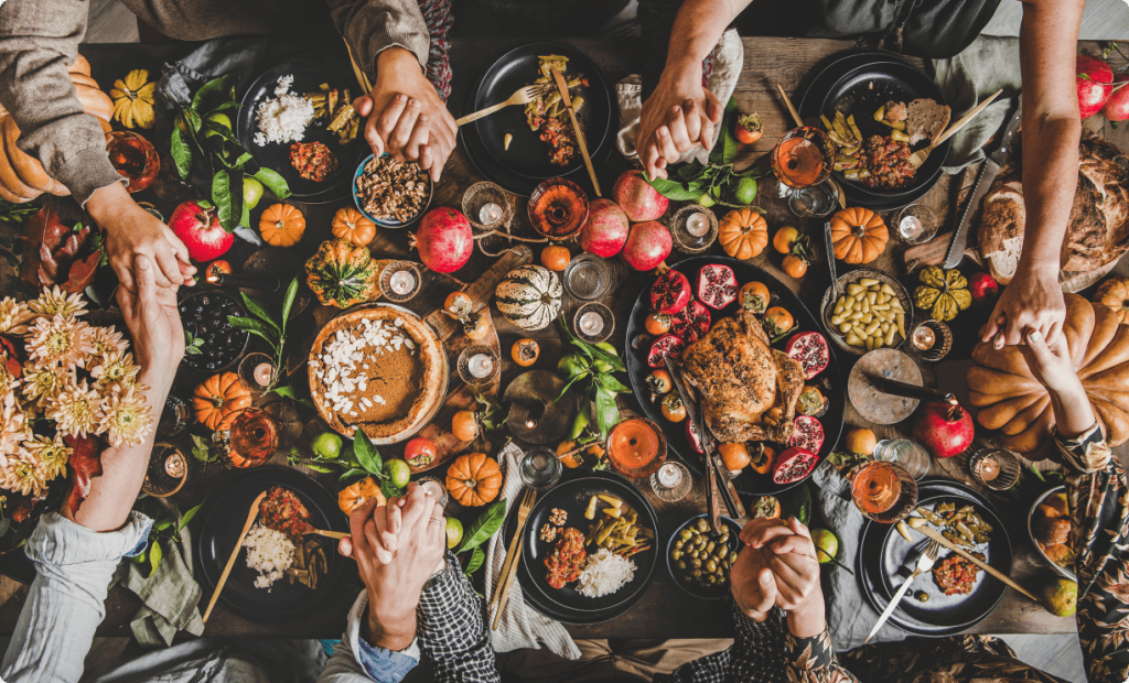 Family seated at the table and offering a prayer before starting Thanksgiving dinner.