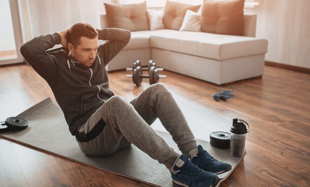 A boy doing warm up exercise on a yoga matt in his home