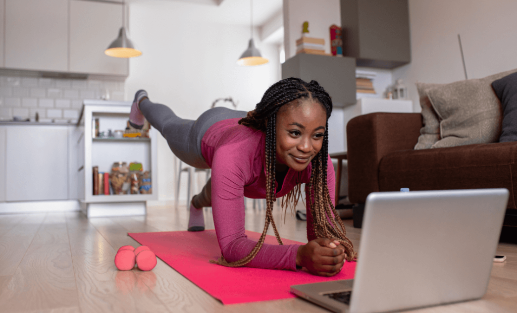 A girl watching exercise tutorial on her laptop and doing a plank.