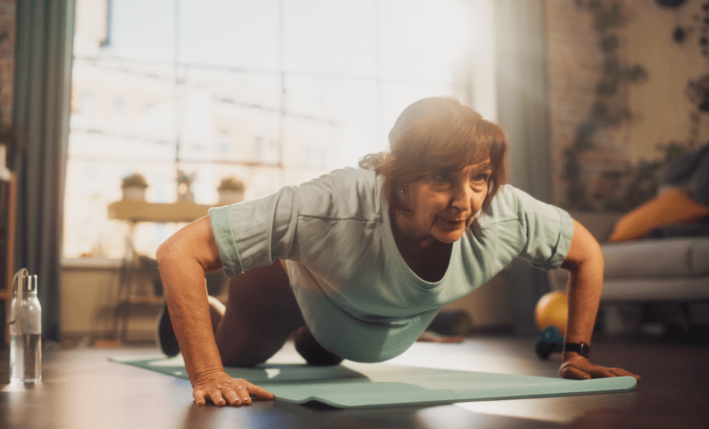 An aged women doing planks on an exercise matt in her house