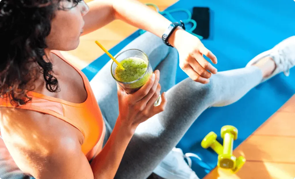 A fit girl wearing smart watch and drinking a healthy juice.