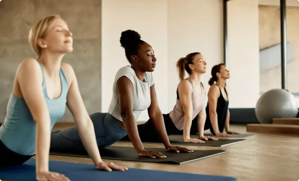 A group of girls practicing meditation poses on yoga mats at Vision Sports Club.