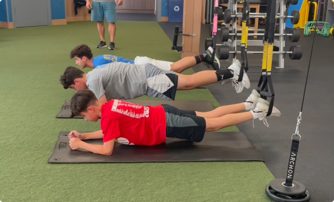 High school athletes at vision sports club practising TRX planks