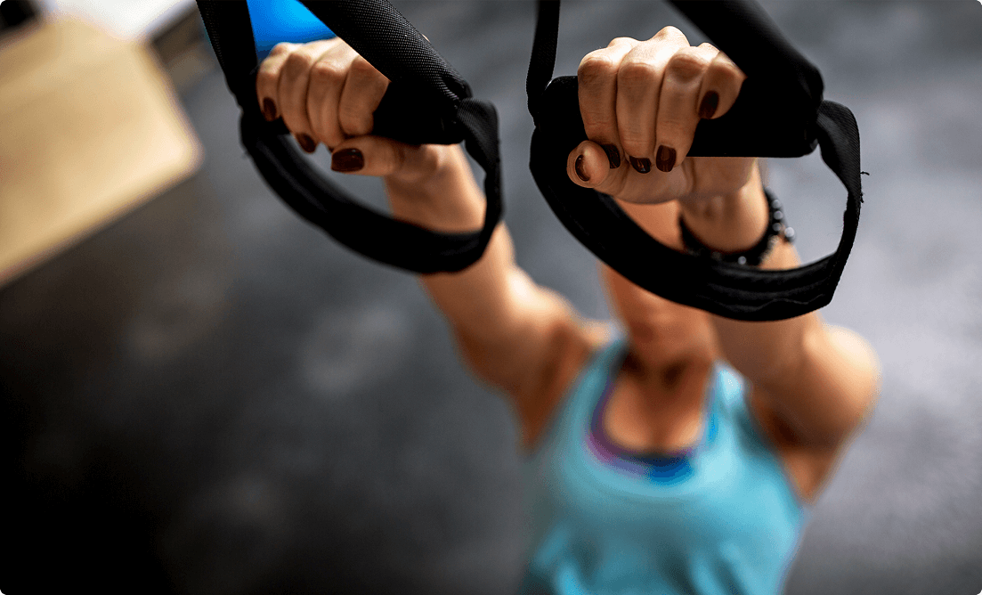 Female athlete holding TRX straps, performing a strength and stability exercise at Vision Elite Training.