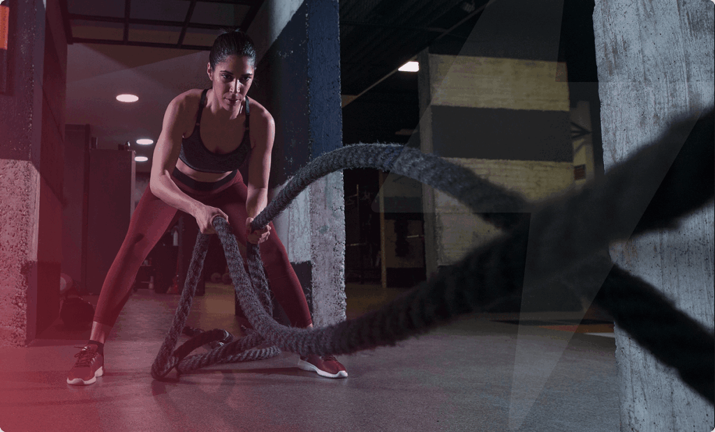 Female athlete performing battle rope exercise demonstrating structured strength training for long-term health at Vision Elite training facility